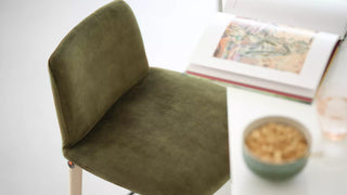 Détail d'un tabouret Mobitec Rob en velours vert avec livre et bol