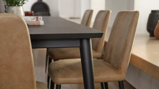 Lifestyle image of cognac Mobitec Rob chairs at a black table in a kitchen