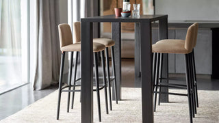 Lifestyle image of camel Mobitec Rob bar stools at a high black table in a kitchen