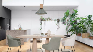 Photo d'ambiance de chaises Mobitec Saga vertes à une table ronde en bois dans une cuisine avec plantes