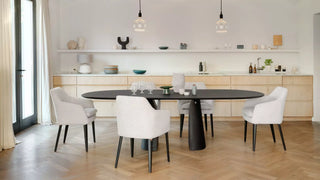 Photo d'ambiance de chaises pivotantes Mobitec Saga blanches à une table ovale noire dans une salle à manger lumineuse