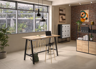 Lifestyle image of a Buronomic Alto two-door bookcase in black and Nebraska by a high table