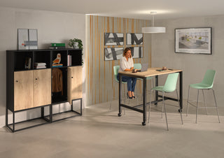 Lifestyle image of a Buronomic Locker Eko two-door locker in black and Nebraska by a high table