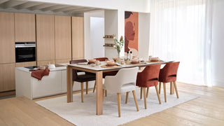 Lifestyle image of white and rust Mobitec Lena chairs at a wooden table in an open kitchen