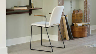 Lifestyle image of a white Mobitec Pamp chair with wooden armrests at a wall desk