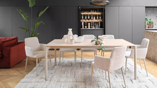 Lifestyle image of white Mobitec Rob armchairs at a long table with a red sofa
