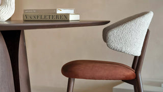 Detail of a Mobitec Toro chair with bouclé back and rust seat at a dark table